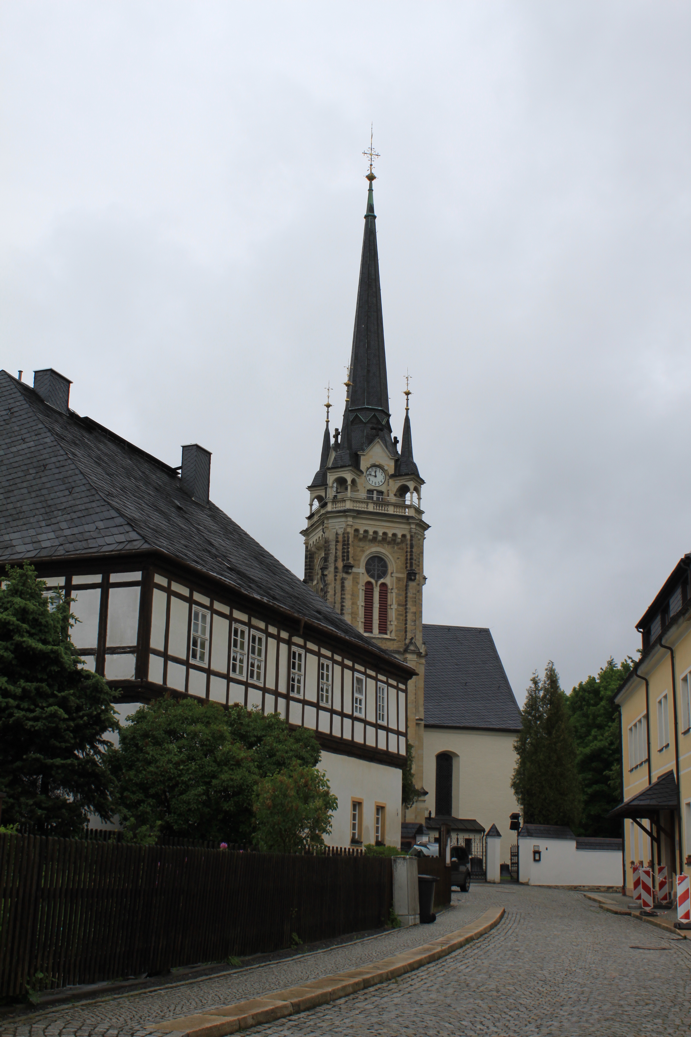 Das Foto zeigt die Kirche in Elterlein. Im Vordergrund ist ein Fachwerkhaus zu sehen. 